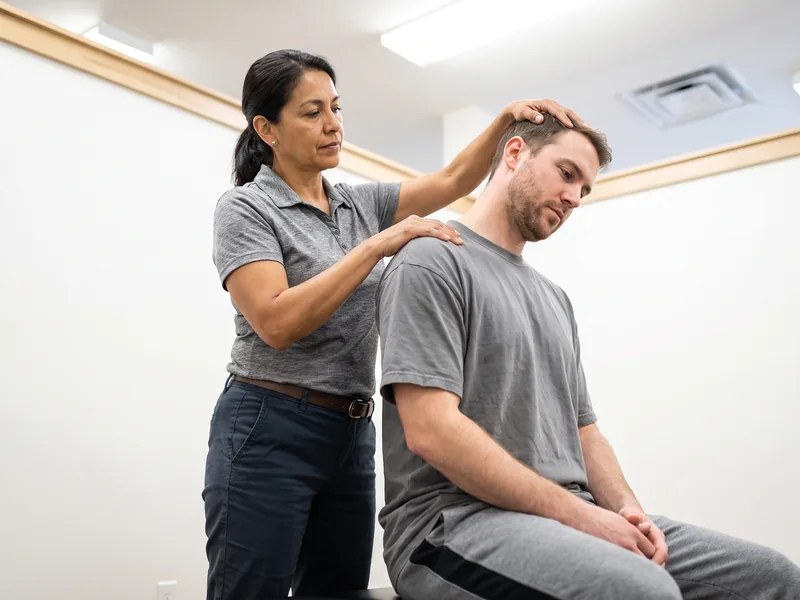 Physical therapist assessing a patient's neck and head movement after a concussion